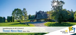 Grünfläche mit Bäumen und einem Gebäude im Hintergrund an einem sonnigen Tag.